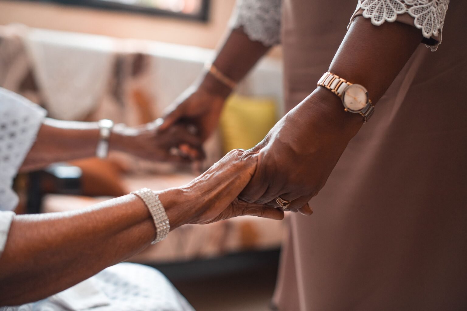 Mains jointes entre un aidant familial et son proche âgé, symbole de soutien et d'accompagnement au quotidien
