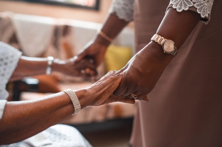 Mains jointes entre un aidant familial et son proche âgé, symbole de soutien et d'accompagnement au quotidien
