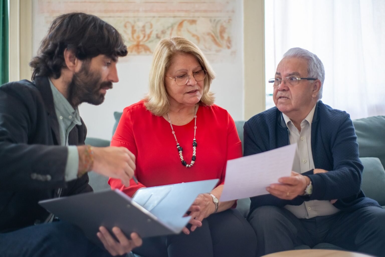 Un aidant familial aide un couple de proches âgés à examiner des documents pour un dossier MDPH