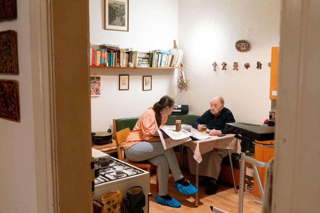 Une jeune aidante et un homme âgé assis à table, en train d'organiser ensemble les démarches du maintien à domicile