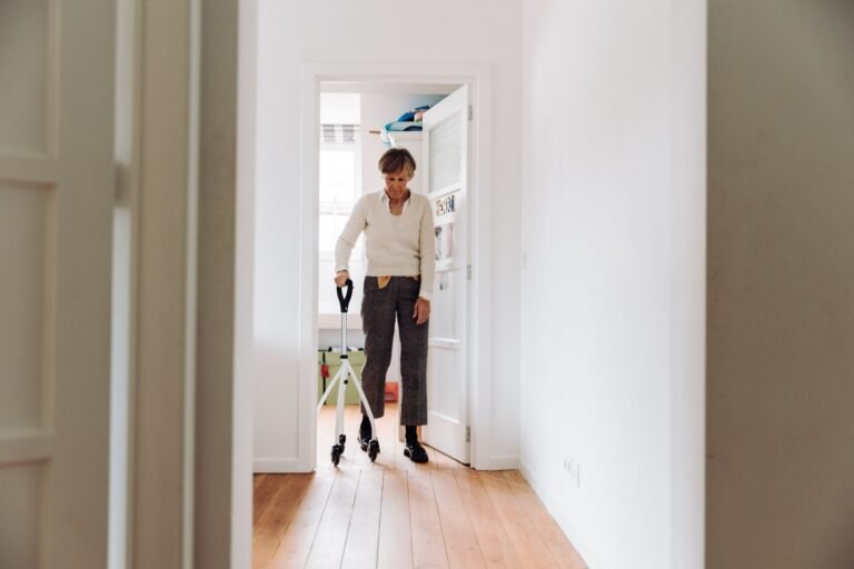 Personne âgée se déplaçant avec un déambulateur dans un couloir de son domicile, bien éclairé et dégagé