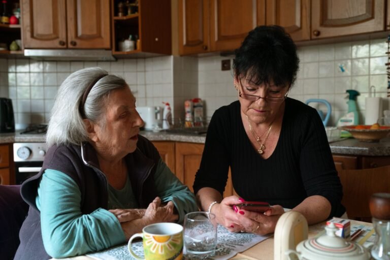 Une aidante et une personne âgée partagent un moment dans une cuisine, illustrant l'accompagnement au quotidien