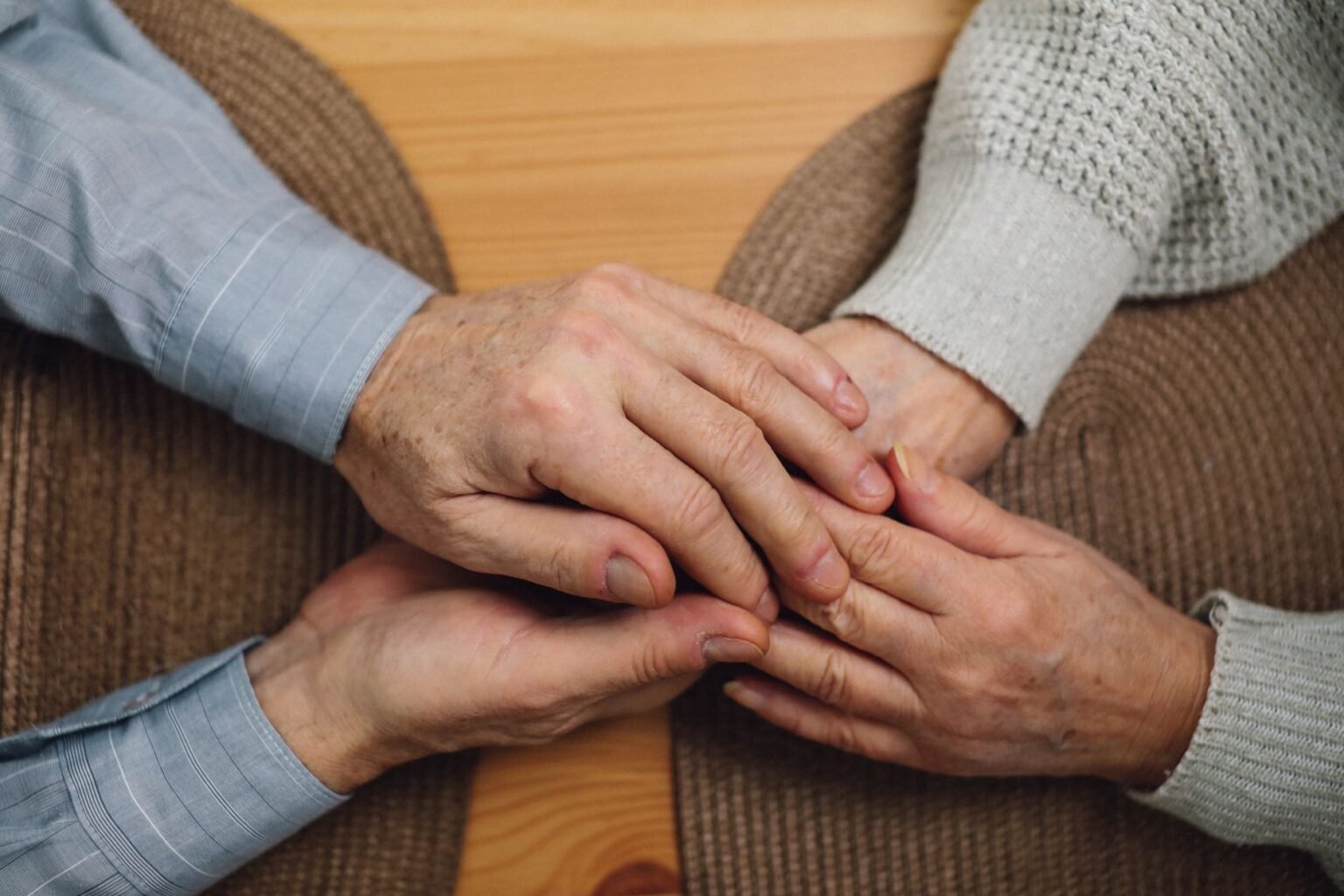 Mains d'un aidant tenant celles d'une personne âgée en signe de réconfort