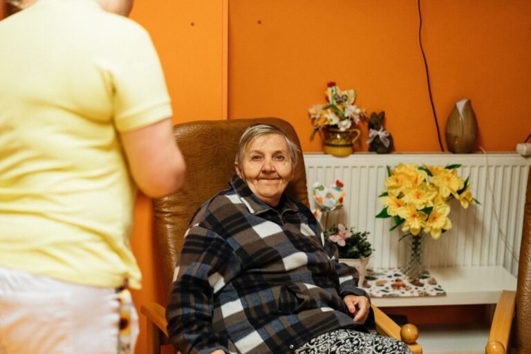 Une aidante assise auprès d'une personne âgée, dans une relation de confiance et de bienveillance
